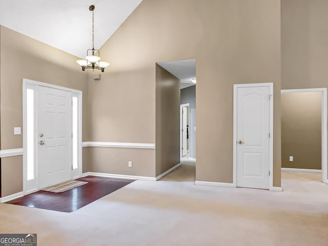 carpeted entrance foyer featuring a chandelier and high vaulted ceiling