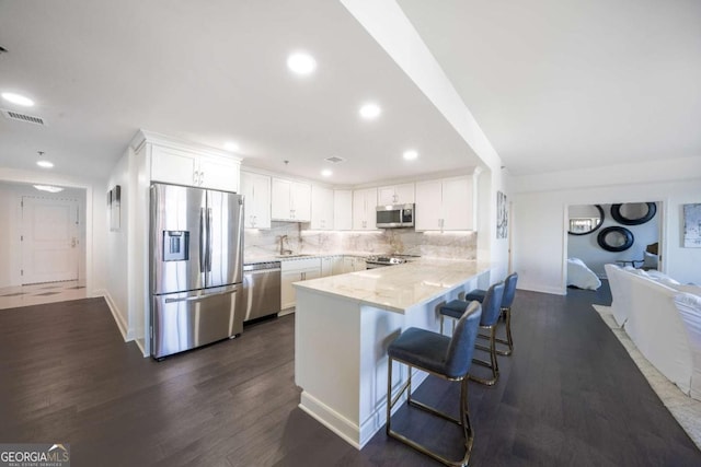 kitchen featuring white cabinetry, a breakfast bar, stainless steel appliances, and kitchen peninsula