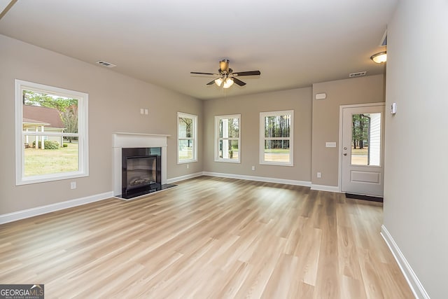 unfurnished living room with ceiling fan, a wealth of natural light, and light wood-type flooring