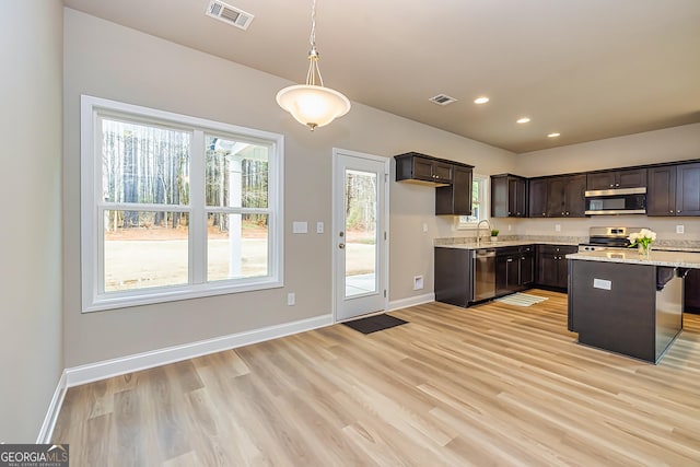 kitchen with a breakfast bar, sink, dark brown cabinets, hanging light fixtures, and stainless steel appliances