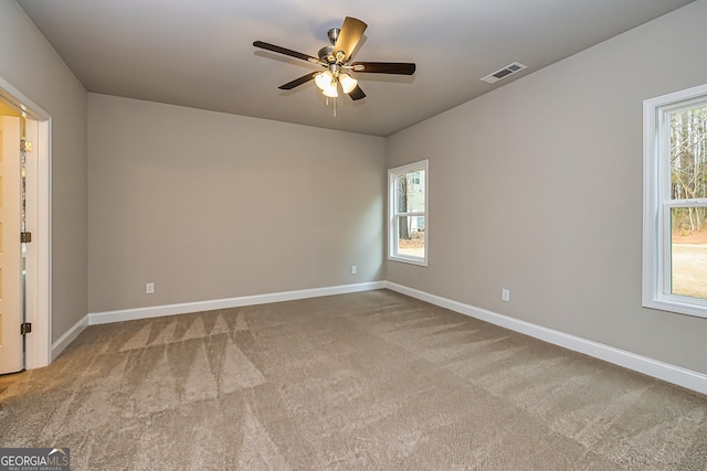 carpeted spare room featuring ceiling fan and a wealth of natural light