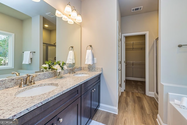 bathroom featuring vanity, hardwood / wood-style floors, plus walk in shower, and a chandelier