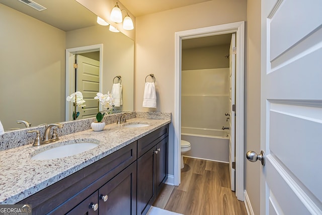 full bathroom with wood-type flooring, tub / shower combination, vanity, and toilet