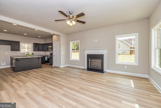 unfurnished living room with ceiling fan and light wood-type flooring