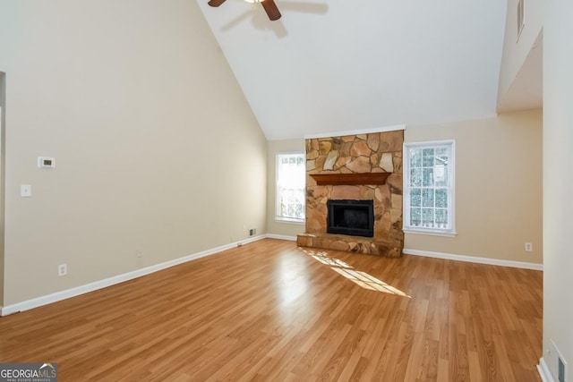 unfurnished living room with high vaulted ceiling, a fireplace, light wood-type flooring, and a wealth of natural light