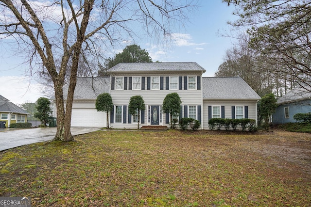 colonial inspired home featuring a garage and a front yard