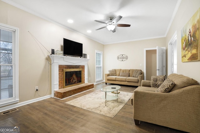 living room with a brick fireplace, ornamental molding, dark hardwood / wood-style floors, and ceiling fan