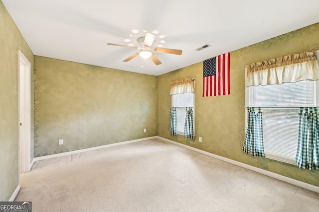unfurnished room with a healthy amount of sunlight, visible vents, carpet floors, and a ceiling fan