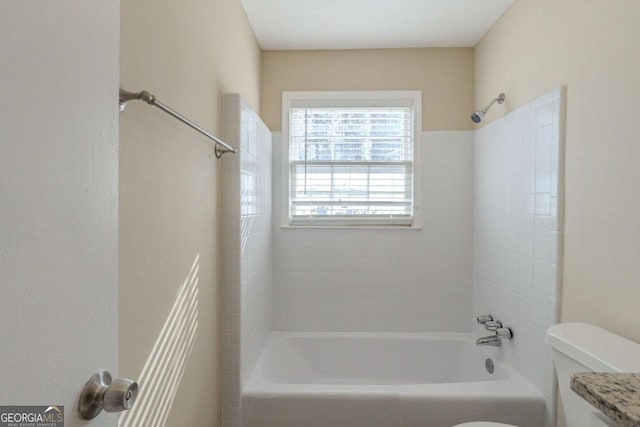 bathroom with toilet and tiled shower / bath combo