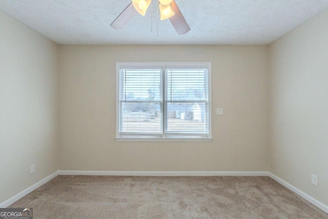 empty room featuring ceiling fan, light colored carpet, and a textured ceiling