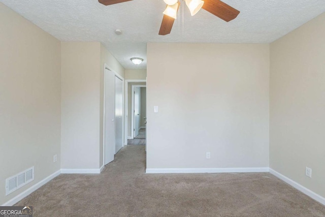 carpeted empty room featuring ceiling fan and a textured ceiling