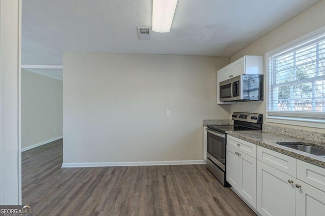 kitchen with white cabinetry, light stone counters, dark wood-type flooring, and appliances with stainless steel finishes