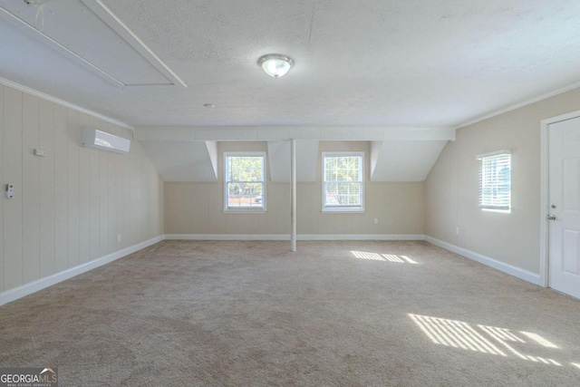 additional living space with light colored carpet, a wall mounted AC, vaulted ceiling, and a textured ceiling