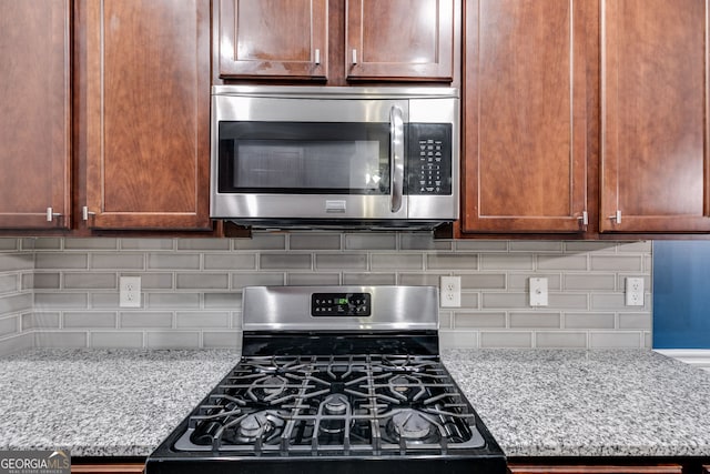 kitchen featuring light stone counters, tasteful backsplash, and stainless steel appliances