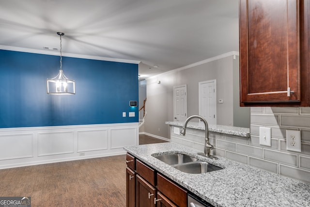 kitchen with hardwood / wood-style floors, decorative light fixtures, sink, light stone counters, and crown molding