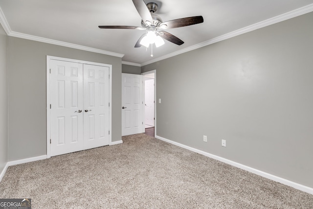 unfurnished bedroom with crown molding, ceiling fan, carpet flooring, and a closet