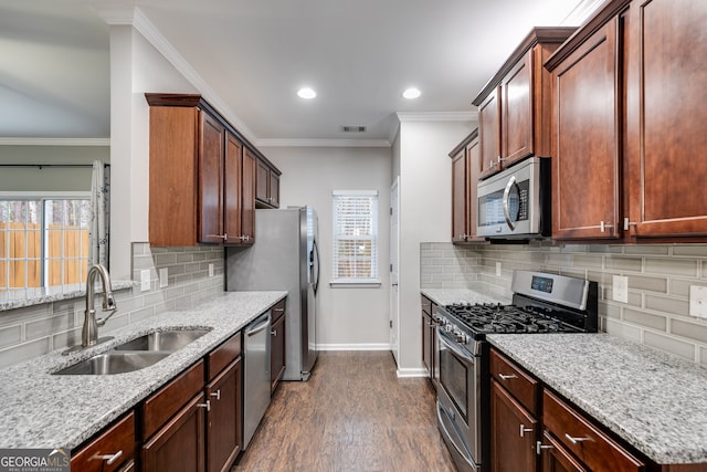 kitchen with sink, crown molding, light stone counters, appliances with stainless steel finishes, and dark hardwood / wood-style flooring