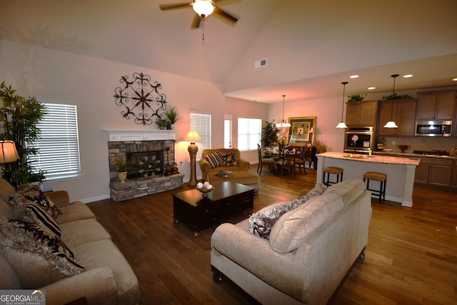 living room featuring high vaulted ceiling, a stone fireplace, ceiling fan, visible vents, and recessed lighting