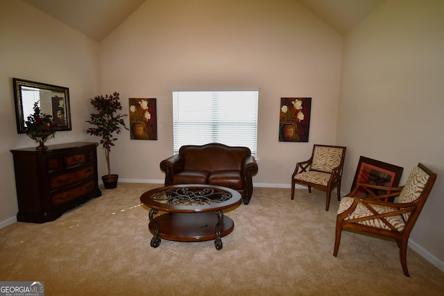 sitting room with carpet floors, baseboards, and high vaulted ceiling