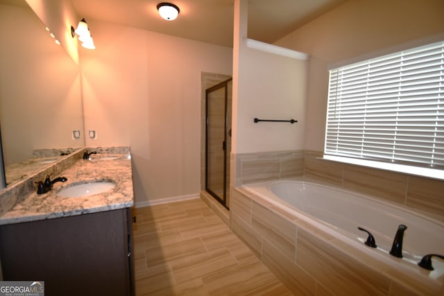 bathroom featuring a bath, a sink, double vanity, a stall shower, and baseboards