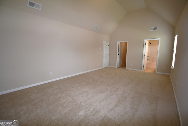 interior space featuring light carpet, baseboards, visible vents, and high vaulted ceiling