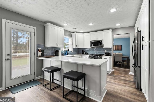 kitchen featuring appliances with stainless steel finishes, white cabinetry, a kitchen breakfast bar, kitchen peninsula, and a barn door