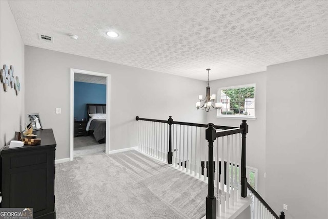 corridor featuring a textured ceiling, a chandelier, and carpet flooring