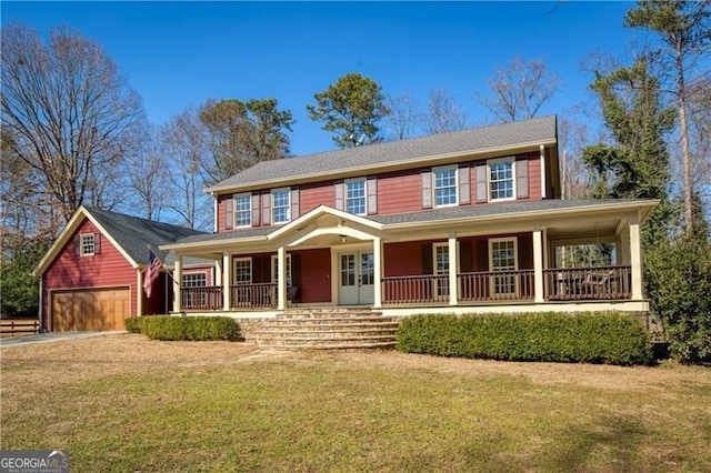 colonial house featuring covered porch, a front lawn, an outbuilding, and a garage