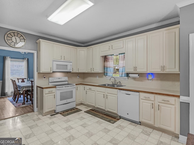 kitchen featuring crown molding, light floors, light countertops, a sink, and white appliances