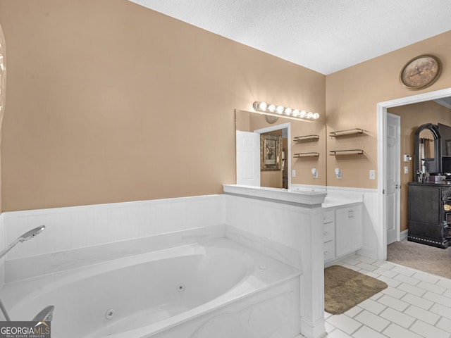 full bathroom with a textured ceiling, a wainscoted wall, vanity, tile patterned floors, and a whirlpool tub