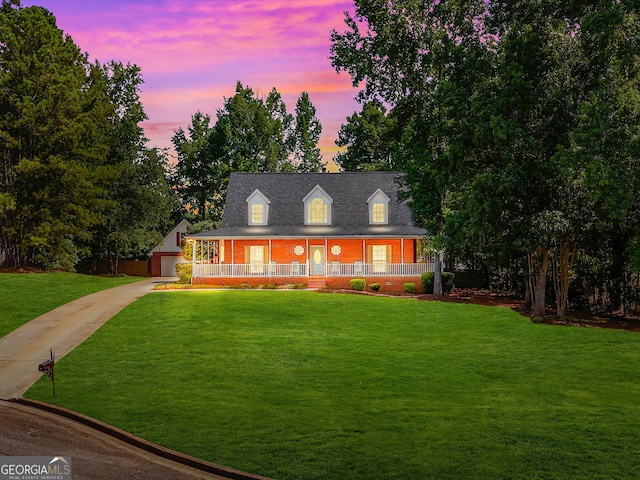 view of front facade with a garage, a porch, a front yard, and brick siding