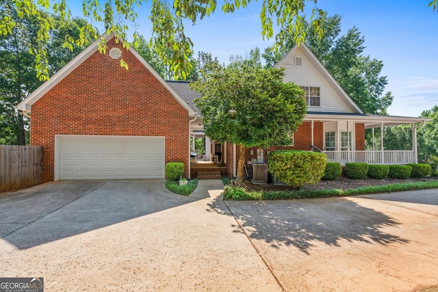 view of front of house with brick siding, a porch, concrete driveway, fence, and a garage