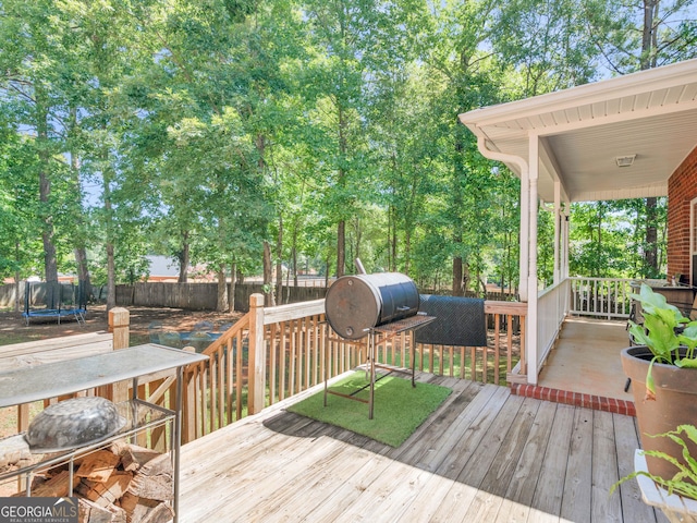 wooden deck with a trampoline and a fenced backyard