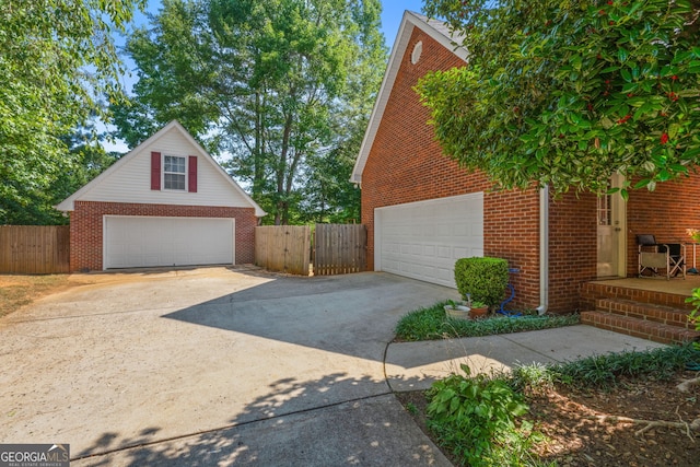 view of property exterior featuring a garage, brick siding, and fence