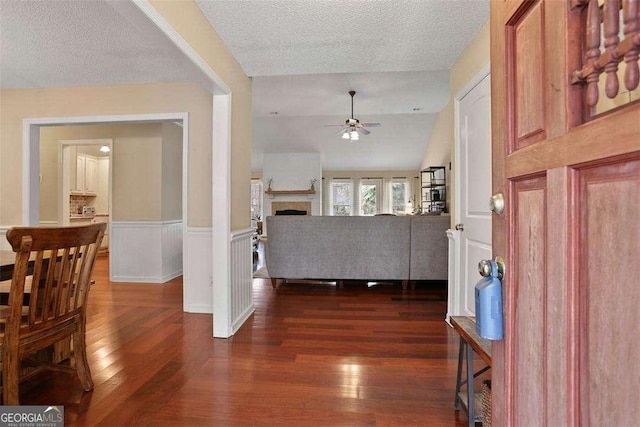 217 E Point Dr, Savannah, GA 31410 - entrance foyer with a ceiling fan, dark wood-style floors, a wainscoted wall, a textured ceiling, and a fireplace