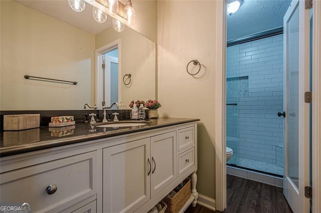 bathroom with hardwood / wood-style floors, an enclosed shower, vanity, a textured ceiling, and toilet