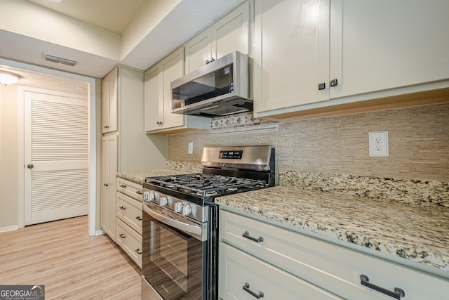 3205 Canyon Point Cir, Roswell, GA 30076 - kitchen featuring appliances with stainless steel finishes, light wood-type flooring, backsplash, and light stone countertops