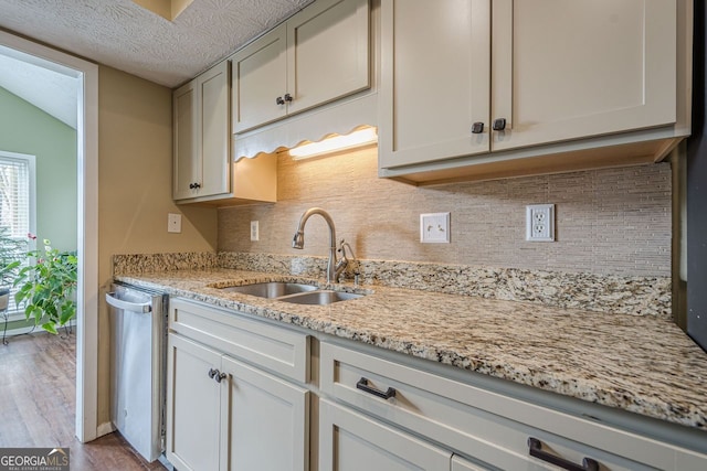 kitchen with sink, backsplash, stainless steel dishwasher, light stone counters, and a textured ceiling