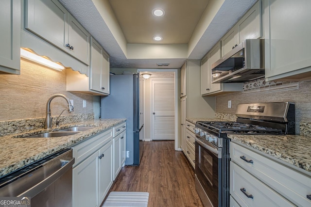 kitchen with a raised ceiling, white cabinetry, appliances with stainless steel finishes, and sink