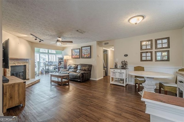 living room with ceiling fan, dark hardwood / wood-style floors, and a textured ceiling