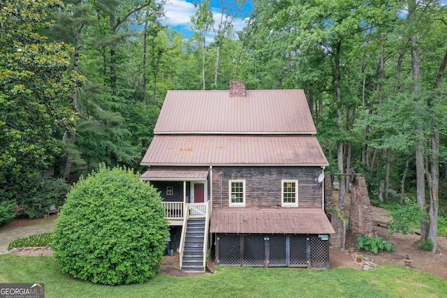 view of front of home with a front lawn, stairway, a chimney, metal roof, and stone siding