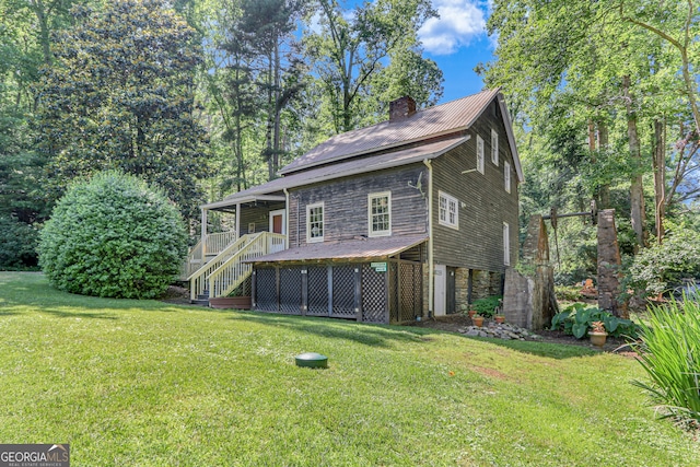 view of front facade featuring stone siding, a lawn, a chimney, and metal roof