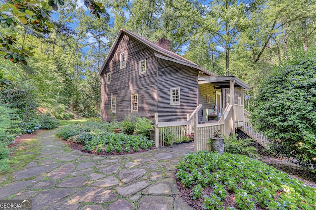 view of property exterior with a chimney and stairs