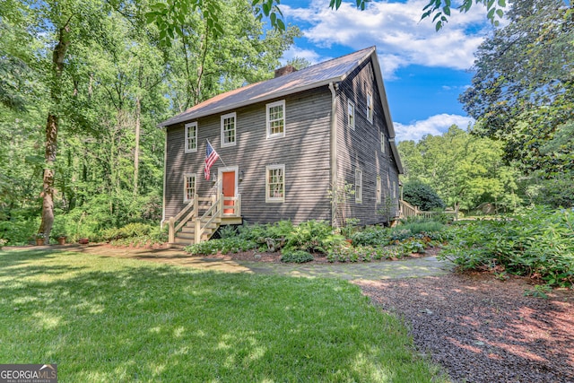 colonial house featuring a chimney and a front yard