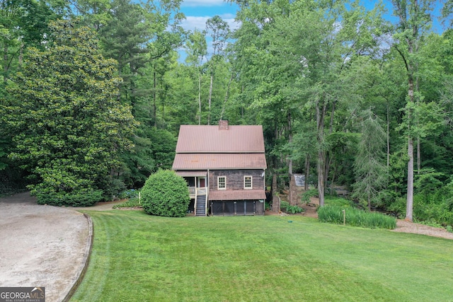 view of front of home featuring a deck, metal roof, stairway, a chimney, and a front yard