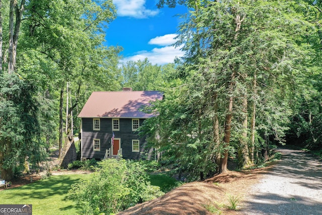 colonial home with driveway, a front lawn, and metal roof