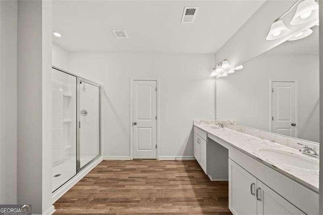 bathroom with hardwood / wood-style flooring, vanity, and walk in shower