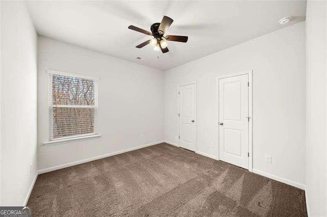 unfurnished bedroom with dark colored carpet and ceiling fan