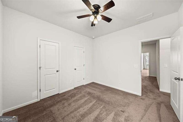 unfurnished bedroom with ceiling fan and dark colored carpet