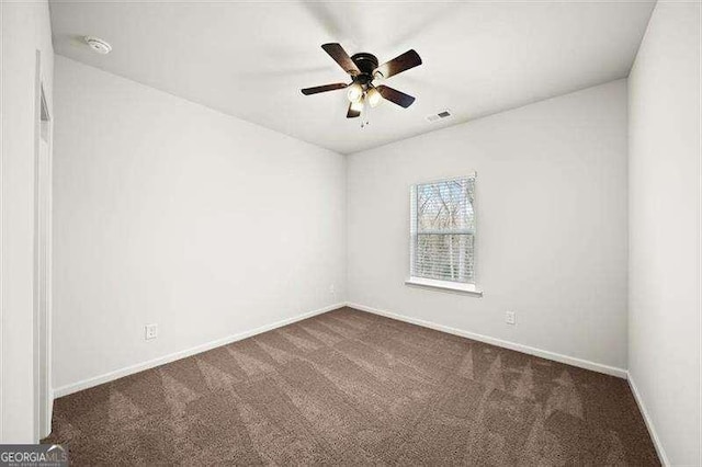 spare room with ceiling fan and dark colored carpet